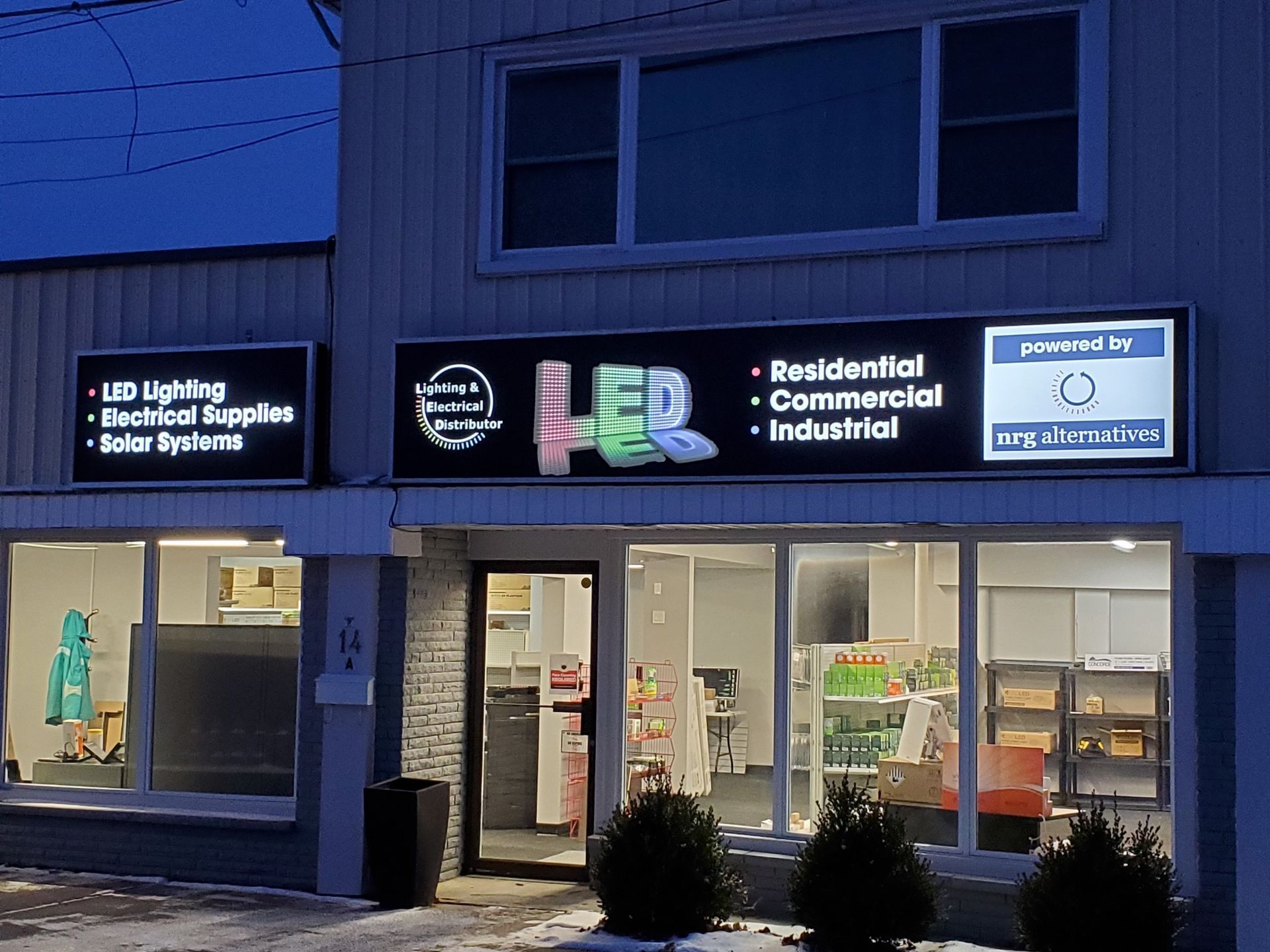 The NRG Alternatives storefront at dusk, its LED sign lit above the showroom windows at 14A North Front Street